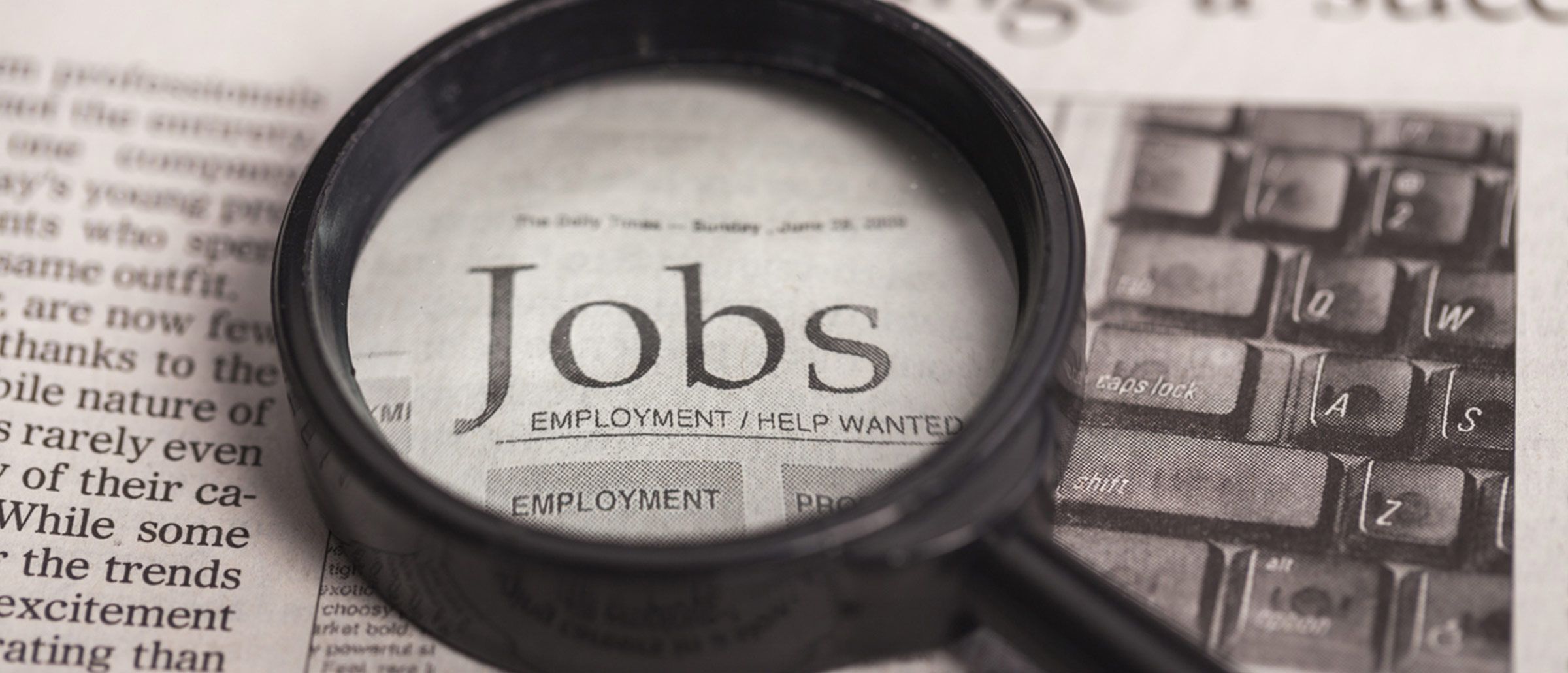 A black magnifying glass set on a piece of paper with the word jobs in focus